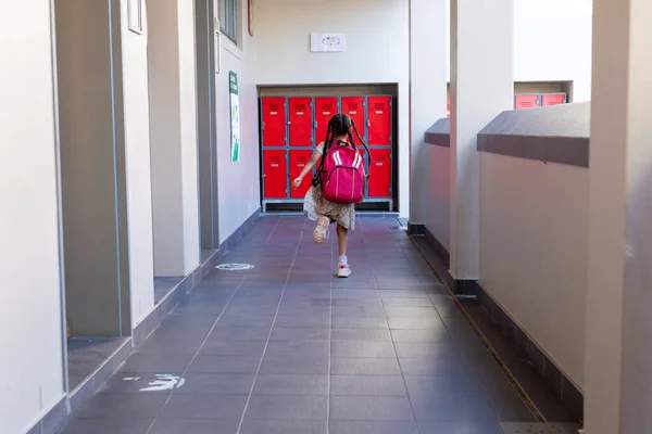 小学时 一个带着红色书包的小学女生在走廊里奔跑 学习和学校 — 图库照片