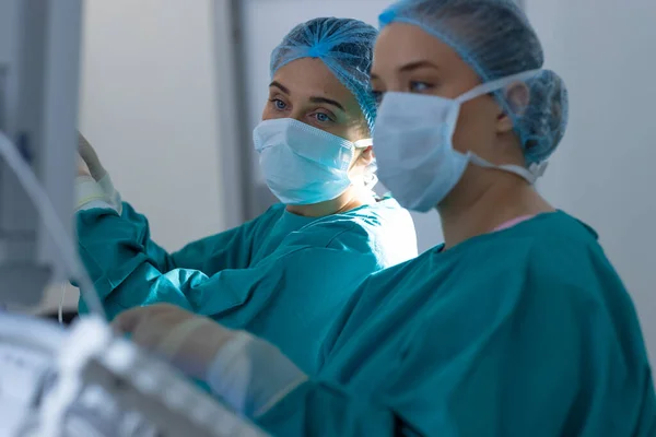 Diverse surgeons wearing surgical gowns operating on patient in operating theatre at hospital. Hospital, surgery, hygiene, teamwork, medicine, healthcare and work, unaltered.