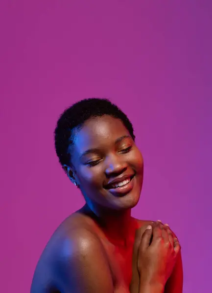 African american woman smiling with eyes closed in blue and red light with purple copy space. Femininity, face, facial expressions, body, skin, makeup, fashion and beauty, unaltered.