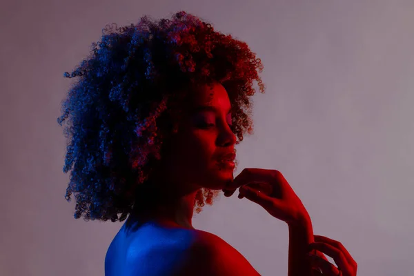 Biracial Γυναίκα Σγουρά Μαλλιά Αγγίζοντας Πηγούνι Μπλε Και Κόκκινο Φως — Φωτογραφία Αρχείου