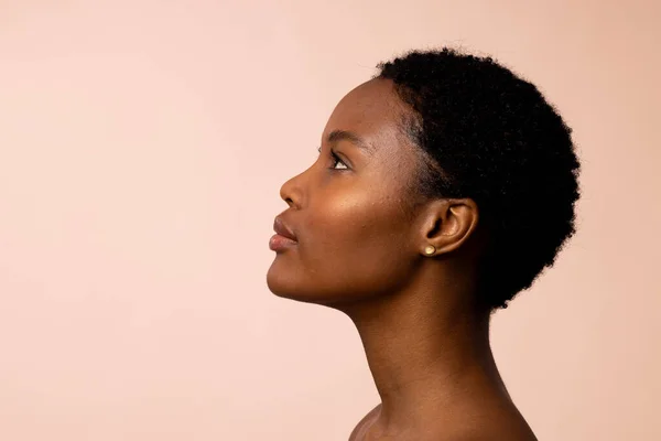 Profile of african american woman with short hair looking up, copy space. Femininity, face, facial expressions, body, skin, makeup, fashion and beauty, unaltered.