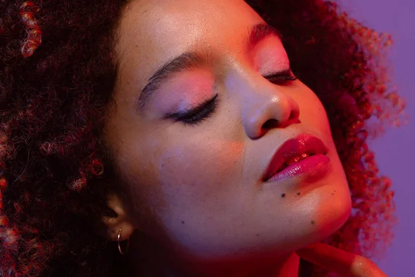 Stock image Biracial woman with curly hair and eyes closed on purple background. Femininity, face, facial expressions, body, skin, makeup, fashion and beauty, unaltered.