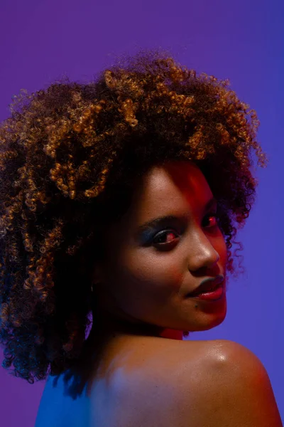 stock image Biracial woman with curly hair and blue eye shadow looking over shoulder. Femininity, face, facial expressions, body, skin, makeup, fashion and beauty, unaltered.