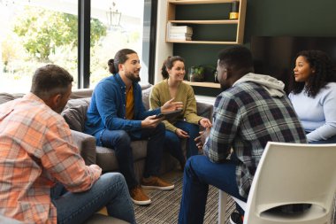 Diverse group of friends and male therapist with tablet in group therapy session. Mental health, therapy, friendship and support,communication, unaltered. clipart