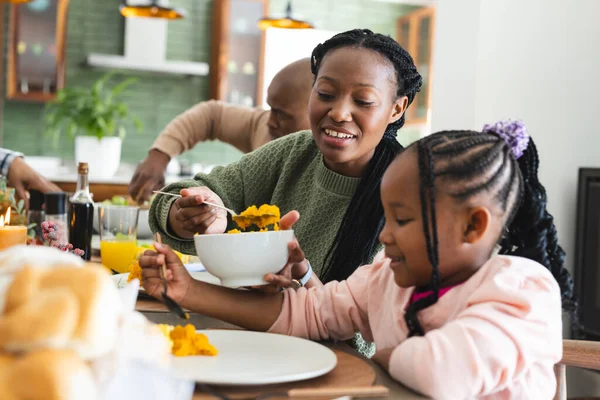 アフリカ系アメリカ人の母親が感謝祭の夕食で娘に食べ物を提供しています 感謝祭 お祝い トータルネス — ストック写真