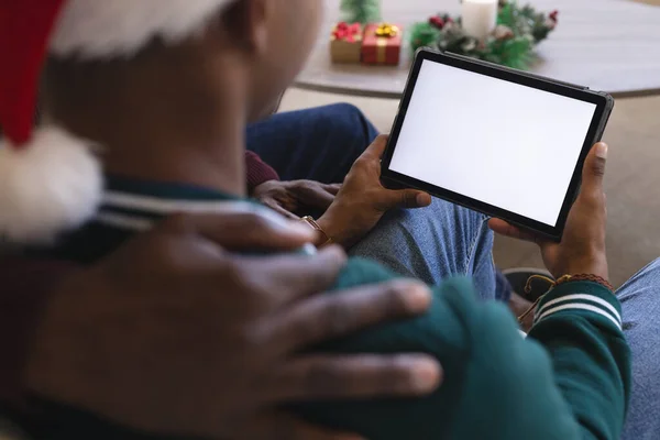 African american father and son having christmas tablet video call, copy space on screen. Communication, family, friends, christmas, celebration, togetherness, tradition and lifestyle, unaltered.
