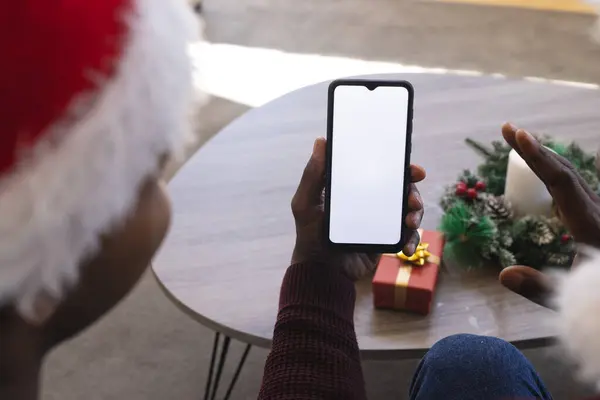 African american father and son having christmas smartphone video call, copy space screen. Communication, family, friendship, christmas, celebration, tradition and lifestyle, unaltered.