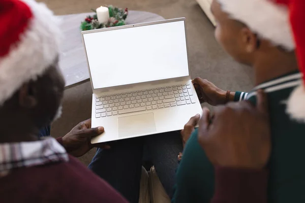 African american father and son having christmas laptop video call, copy space screen. Communication, family, friendship, christmas, celebration, togetherness, tradition and lifestyle, unaltered.