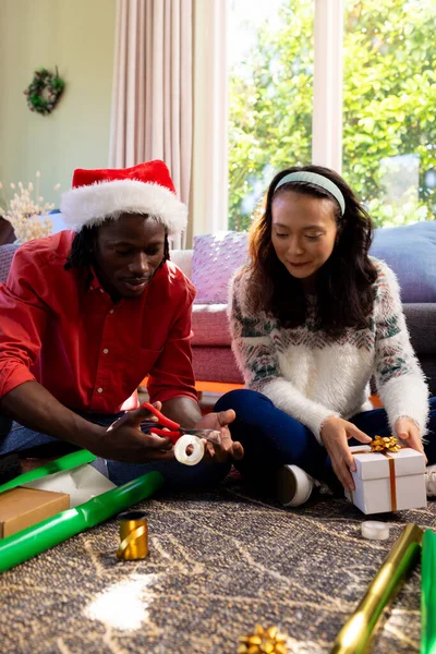Happy Diverse Couple Sitting Floor Wrapping Christmas Gifts Sunny Living — Stock Photo, Image