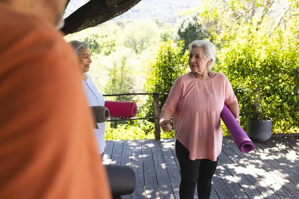 エクササイズマットを保持し 晴れた庭で友達と話し合うハッピーな白人シニア女性 シニアライフスタイル フィットネス 健康的なライフスタイル — ストック写真