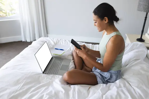 ベッドルームのコピースペースとノートパソコンを使用してスマートフォンとノートブックを持つハッピーな女性 国内生活 ライフスタイル 変わらない — ストック写真