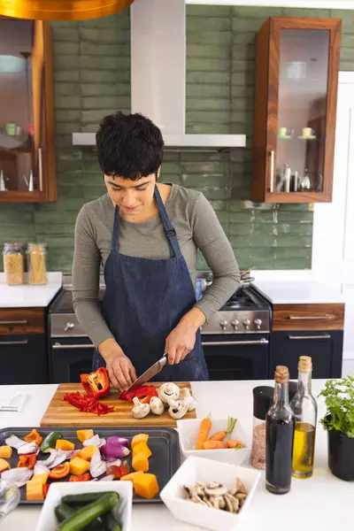 Happy biracial woman preparing food, chopping vegetables in kitchen at home, copy space. Cooking, food, domestic life and healthy lifestyle, unaltered.
