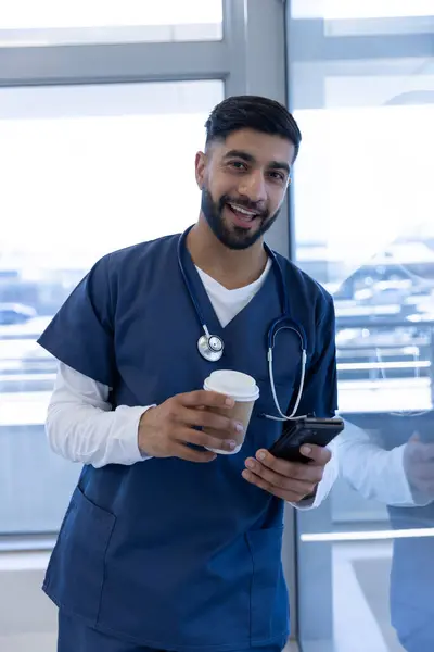 Retrato Del Feliz Médico Birracial Masculino Usando Teléfono Inteligente Sosteniendo —  Fotos de Stock