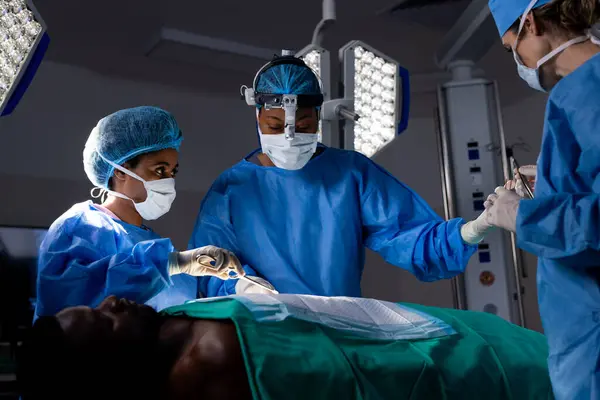 病院の手術室で手術を行うフェイスマスクを持つ多様な女性医師 医療サービス 変わらない — ストック写真