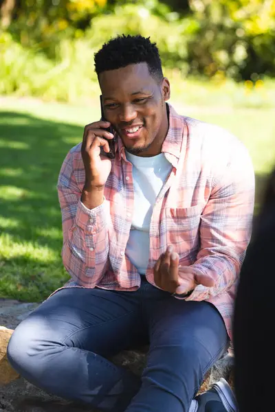 ハッピーアフリカ系アメリカ人男性が階段に座って 晴れた庭でスマートフォンで話し スペースをコピーします アウトドア テクノロジー コミュニケーション 変わらない — ストック写真