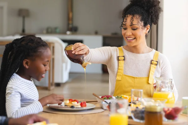 ハッピーアフリカ系アメリカ人の母親は 自宅でダイニングルームで果物にメープルシロップを注いで スペースをコピーします 幼少期 食べ物 飲み物 家庭生活 変わらない — ストック写真