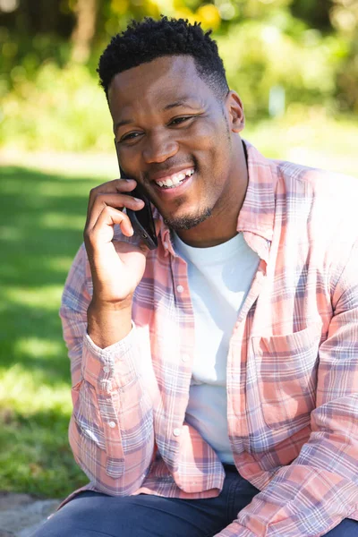 Gelukkig Afrikaans Amerikaanse Man Zit Trap Praten Smartphone Zonnige Tuin — Stockfoto