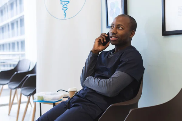 非洲裔美国男性医生在医院候诊室用智能手机交谈 工作和医院 未加改动 — 图库照片