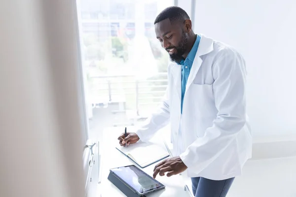 アフリカ系アメリカ人の男性医師がタブレットを使用し 病院の部屋でメモを取ります コミュニケーション 変わらない — ストック写真