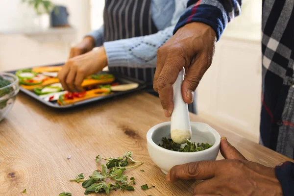 Hands of diverse senior couple preparing healthy meal with vegetables in kitchen. Lifestyle, retirement, senior lifestyle, food, cooking, togetherness and domestic life, unaltered.