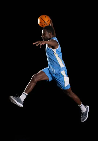 African American man in mid-air basketball action. Athletic prowess shines as he performs a dynamic jump shot on the court.