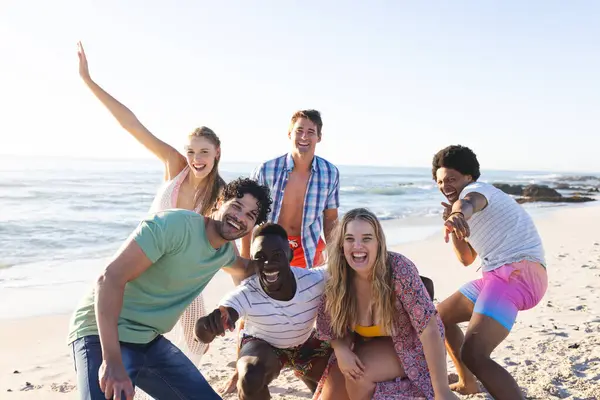Diverse group of friends enjoy a day at the beach. Smiling and posing for a photo, they capture the essence of summer fun outdoors.
