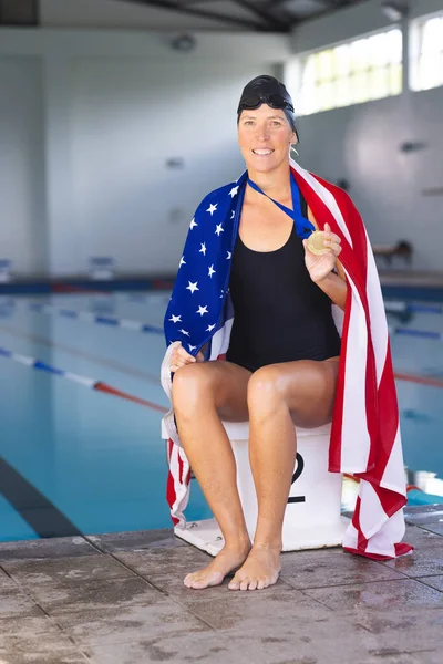 白人女性がプールサイドでアメリカ国旗を掲げ メダルとコピースペースを持った 彼女は誇りと功績を誇り 水泳の勝利の後 — ストック写真