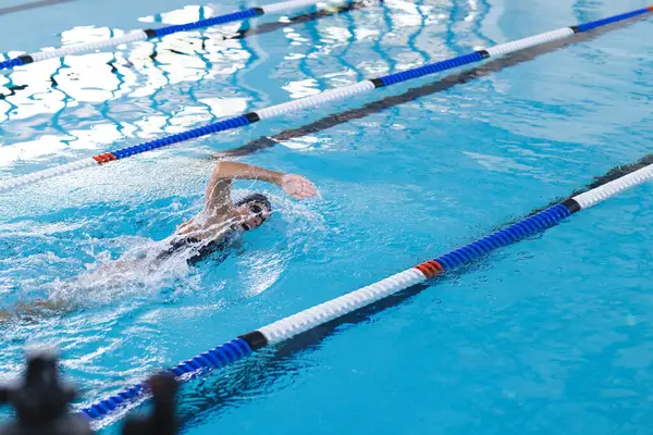 コピースペース付きの屋内プールでのアクションで泳ぎます イメージはスポーツのダイナミックな動きと競争の精神をキャプチャします — ストック写真