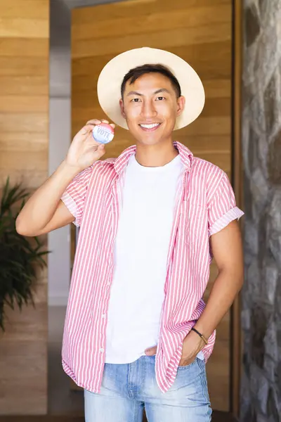 Young Asian Man Smiles Holding Vote Badge Stands Confidently Casual — Stock Photo, Image