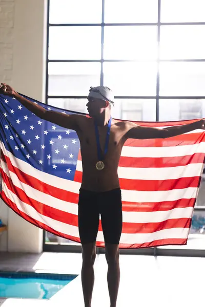 年轻的伯利兹男子运动员在游泳池庆祝胜利 当他用奖牌展示美国国旗时 他的骄傲和成就感闪烁着光芒 — 图库照片