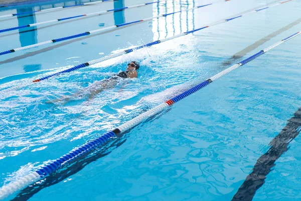 A swimmer practices in a pool, with copy space. The image captures a moment of athletic training in an indoor swimming facility.
