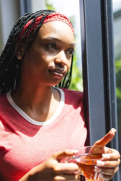 Young African American Woman Gazes Out Window Holding Cup Tea — Stock Photo, Image