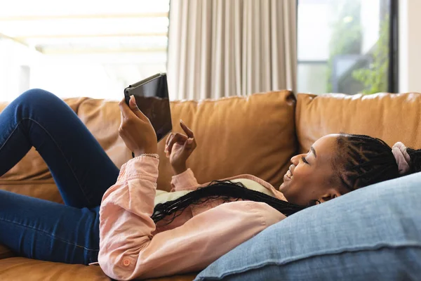 Joven Mujer Afroamericana Descansa Sofá Absorta Tableta Ella Está Relajada — Foto de Stock