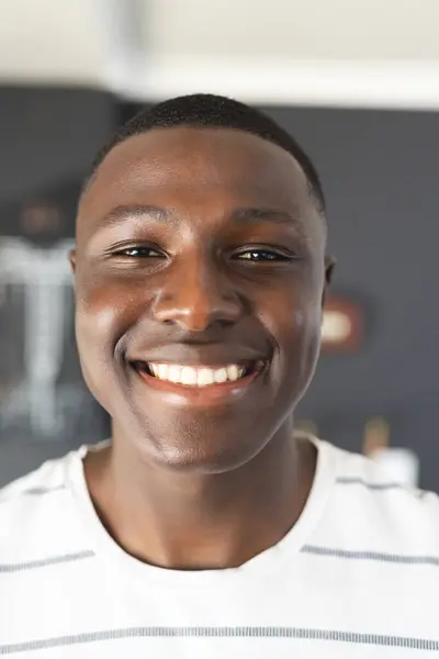 一个年轻的非裔美国人 穿着一件白色条纹衬衫 面带微笑 他快乐的表情和随意的穿着表明他的心情轻松而快乐 免版税图库图片