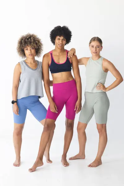 3人の女性が自信を持ってスポーツウェアを着ています このグループには 若い白人女性 若い女性が含まれ 多様性と強さを示しています ロイヤリティフリーのストック画像