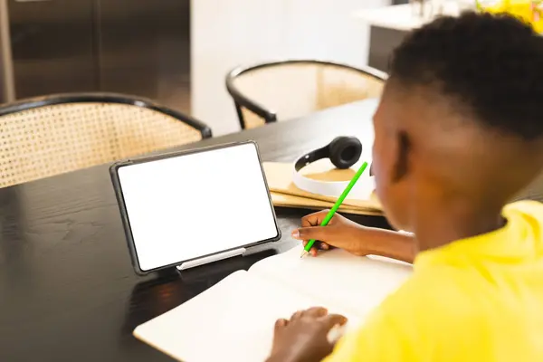 Afroamerikanischer Junge Schreibt Hause Notizbuch Tablet Mit Leerem Bildschirm Der Stockfoto