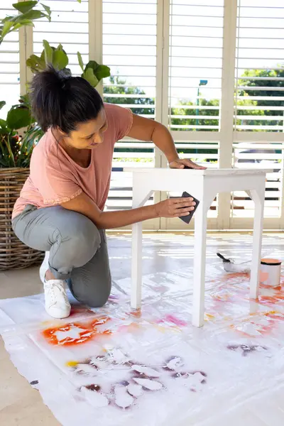 Mature Biracial Woman Painting Stool Home Upcycling Project Wearing Casual Stockbild