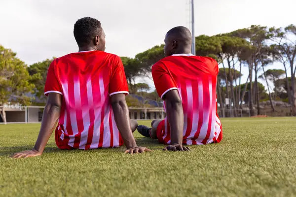 Два Афроамериканских Юных Спортсмена Сидят Траве Открытом Воздухе Красных Майках — стоковое фото