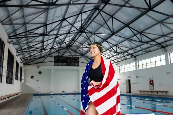 Young Biracial Female Swimmer Standing Pool Indoors Wrapped American Flag — ストック写真
