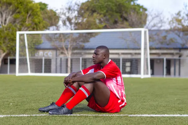Afrikkalainen Amerikkalainen Nuori Urheilija Istuu Jalkapallokenttä Ulkona Etsivät Harkittuja Kopioi kuvapankin valokuva
