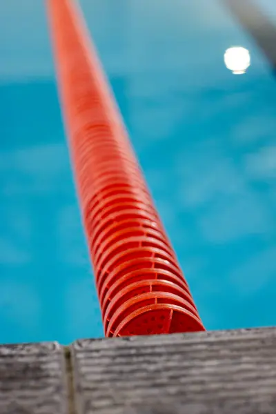 赤いレーンは屋内で青いスイミングプールに広がっています ディバイダーと水のテクスチャと色のコントラストに焦点を当てたクローズアップビュー ロイヤリティフリーのストック写真