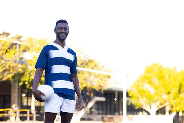 Молодой Афроамериканский Спортсмен Держит Мяч Регби Стоит Поле Открытом Воздухе Стоковое Фото