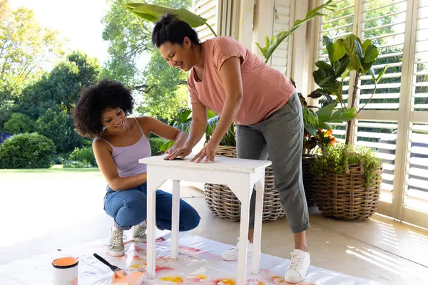 Mama Biracială Fiica Adultă Pictează Mobilier Afara Casei Într Proiect Imagine de stoc