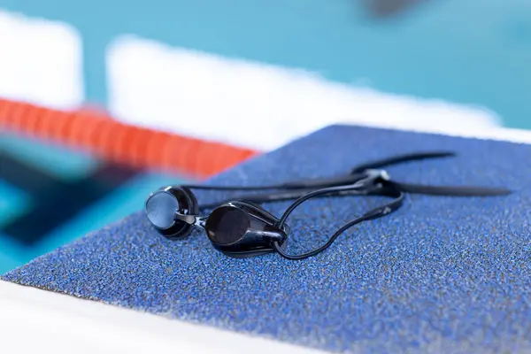 游泳护目镜在室内游泳池边休息 复制空间 蓝色纹理表面和背景中的水 营造平静的氛围 免版税图库图片
