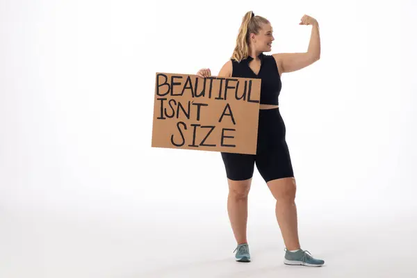 Blanke Jonge Vrouw Size Model Witte Achtergrond Holding Poster Flexing Rechtenvrije Stockafbeeldingen