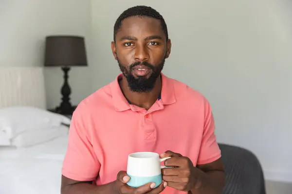 Hombre Afroamericano Sosteniendo Taza Sentado Casa Haciendo Una Videollamada Tiene Imagen De Stock