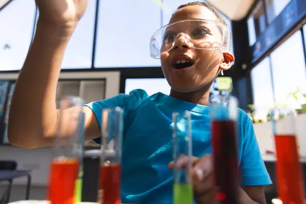 stock image Biracial boy engages in a science experiment at school in the classroom. His excitement is evident as he learns about chemical reactions.