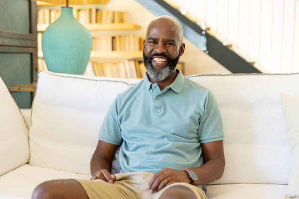 At home, Smiling man sitting on couch at home, enjoying relaxed moment indoors. Relaxation, comfort, lifestyle, happiness, leisure, unaltered — Stock Image Home Smiling Man Sitting Couch Home Enjoying Relaxed Moment Indoors Royalty Free Stock Photos