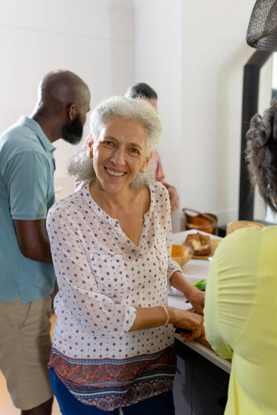 At home, Smiling senior woman preparing food with friends in kitchen, enjoying time together. Cooking, friendship, togetherness, elderly, culinary, happiness, unaltered — Stock Image Home Smiling Senior Woman Preparing Food Friends Kitchen Enjoying Time Royalty Free Stock Images