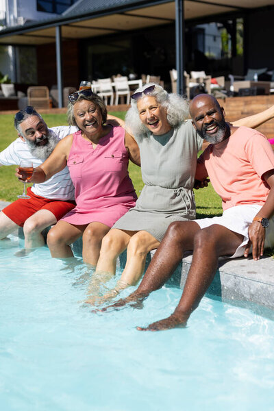 Diverse group of senior friends sitting by pool, enjoying summer day together. Friendship, relaxation, poolside, leisure, seniors, unaltered — Stock Image Diverse Group Senior Friends Sitting Pool Enjoying Summer Day Together Stock Picture